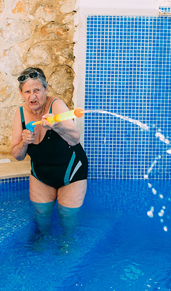 ima170057 Elderly woman with water pistol in swimming pool 