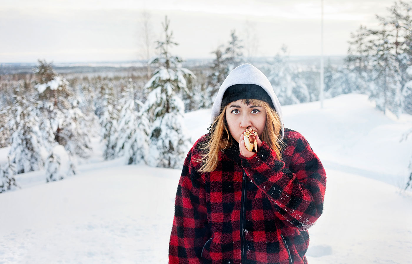 A girl eating sausage among the snowy mountains Image ID: scandinav_eq6p